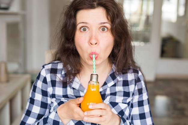 Концепция диеты, здорового образа жизни, детоксикации и людей - выглядит молодая женщина с апельсиновым соком в бутылке