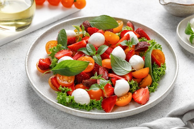 Insalata dietetica e salutare con pomodorini, mozzarella, fragola, basilico e olio d'oliva