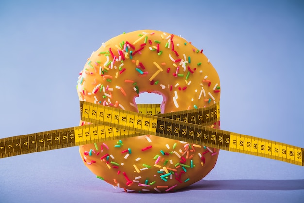 Photo diet. losing weight. donut tying by measuring tape.