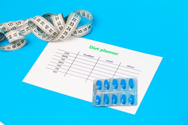 Diet plan and weight loss pills on blue.