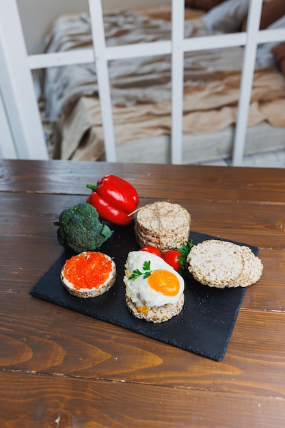 Diet rice breads cherry tomatoes and fresh caviar and parsley on a dark background Snack bread View from above Dietary fiber Healthy Eating