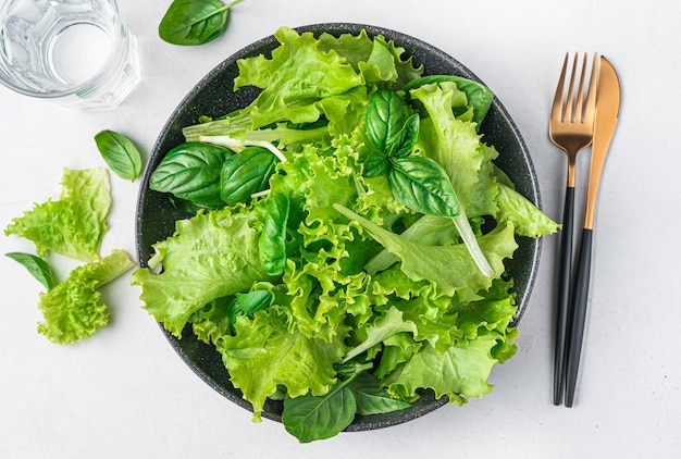 Foto insalata dietetica a base di una miscela di foglie di basilico fresco e lattuga su sfondo grigio