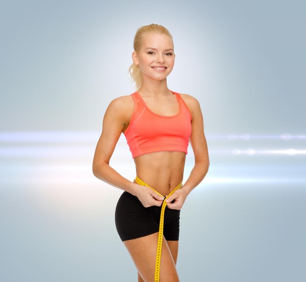 Photo diet, sport, fitness and heath concept - smiling beautiful sporty woman with measuring tape