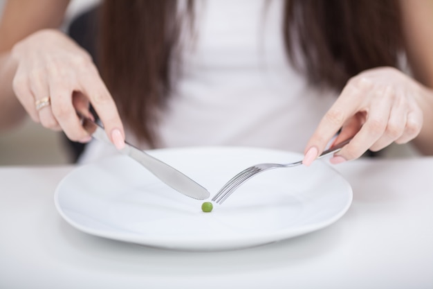 사진 다이어트, 식욕 부진으로 고통, 포크에 완두콩을 넣으려고 노력하는 여자의 자른 이미지