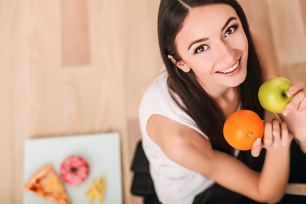 Foto dieta. una giovane donna osserva la sua figura e mangia frutta fresca. il concetto di alimentazione sana.