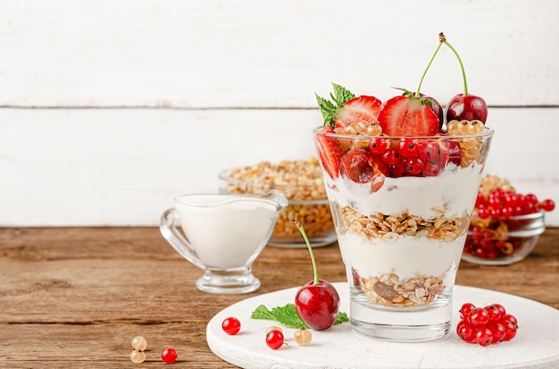 Colazione dietetica di muesli con frutti di bosco e yogurt su fondo di legno bianco. copia spazio