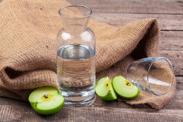 깨끗한 물에 사과 조각과 나무 테이블에 신선한 사과와식이 해독 음료