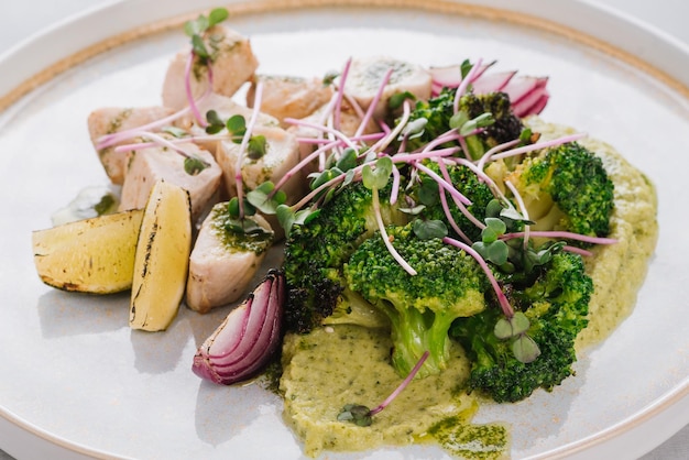 Piatto dietetico con filetto di pollo con broccoli purea di broccoli lime e cipolla su fondo bianco