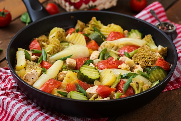 Foto menu dietetico. verdure al vapore con filetto di pollo in padella sul tavolo di legno.