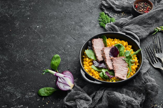 Dietary nutrition Boiled veal with corn and spinach in a black bowl Rustic style