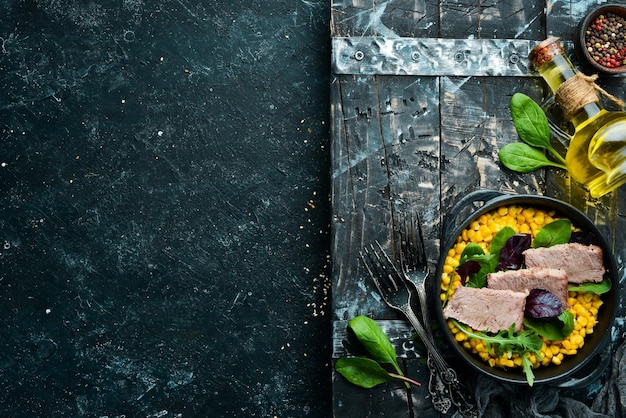 Dietary nutrition Boiled veal with corn and spinach in a black bowl Rustic style