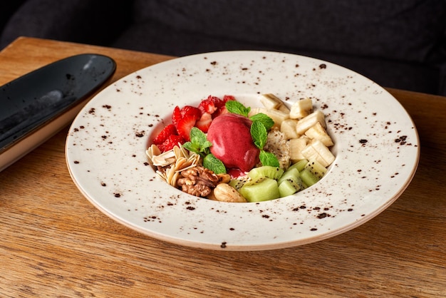 DietFresh tasty mix fruit salad in the bowl on brown wooden table background healthy breakfast weight loss concept