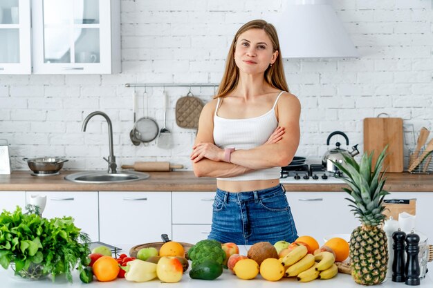 ダイエットのコンセプトダイエット健康的な食品果物と野菜と一緒にキッチンの近くの美しい若い女性