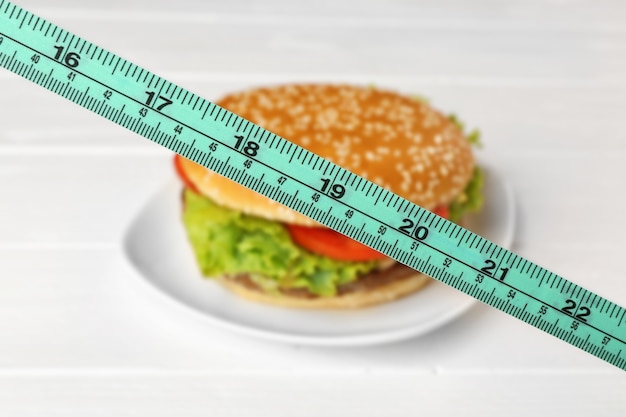 Photo dieting concept. measuring tape and hamburger on plate