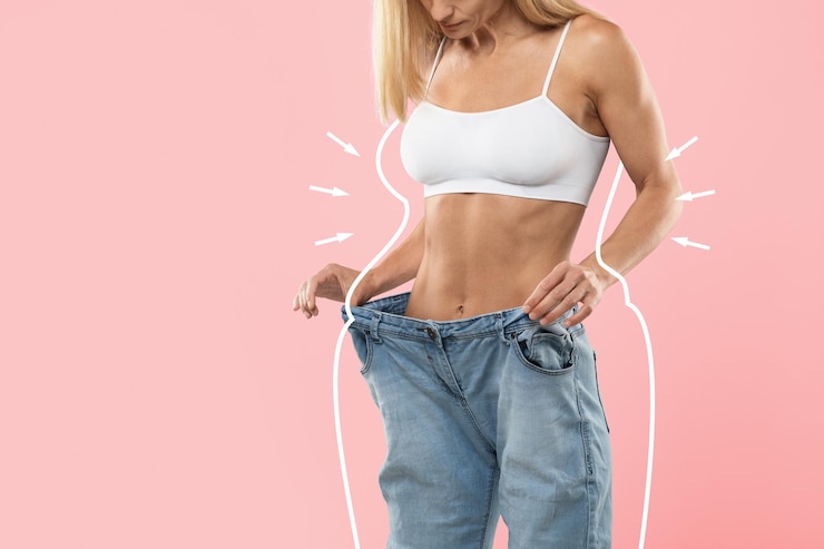 Photo dieting concept slim young lady in oversized jeans standing over pink background
