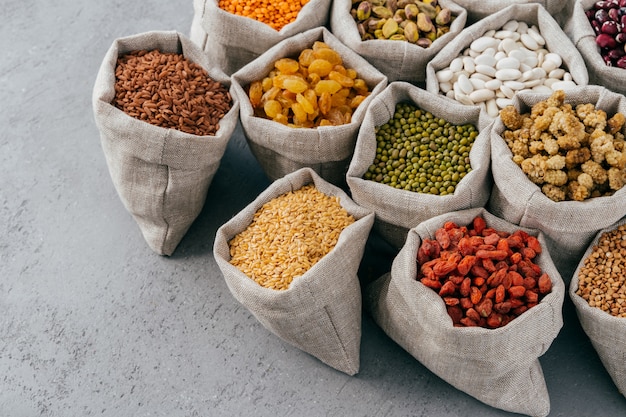 다이어트, 영양 및 건강한 식습관 개념. 삼 베 자루에 단백질이 풍부한 다채로운 곡물 및 말린 과일. 마른 콩과 식물 씨앗.