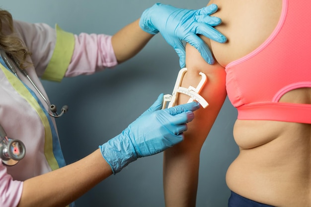 Dietitian doctor taking patient's body fat measurements on arm with fat caliper