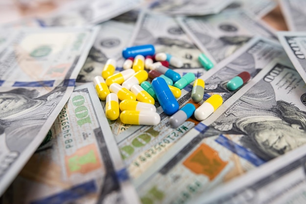 Diffeerent medical pills scattered on dollar paper money as background