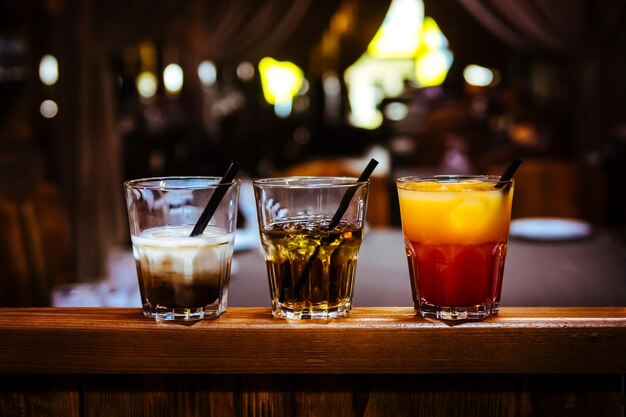 Foto cocktail alcolico diverso con ghiaccio in un bar su un tavolo di legno