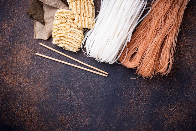 Photo different asian rice noodles on rusty background