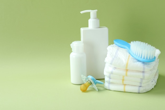 Different baby hygiene accessories on green background