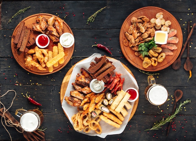 Different beer snack sets on round wooden boards