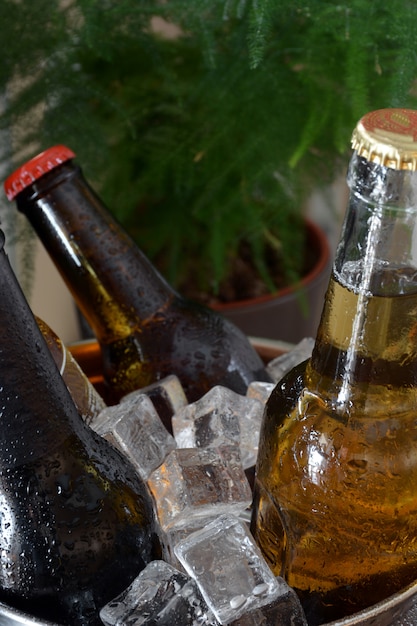 木のテーブルにさまざまなビール。それらを冷たく保つために氷が付いているびんそしてガラスがあります