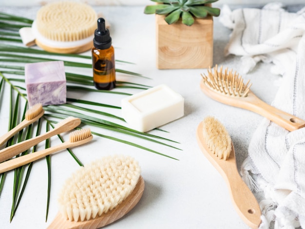 Different body brushes, pumice, bamboo toothbrush, white towel and a piece of soap on a grey background. Zero waste concept. Eco-friendly bath set. Copy space