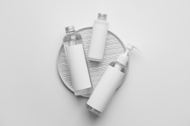 Different bottles of cosmetic products on light background