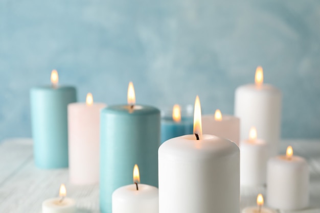 Different burning candles against blue, space for text