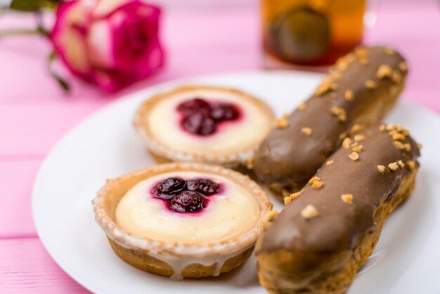 Different cakes with custard and cream and berries on a white plate