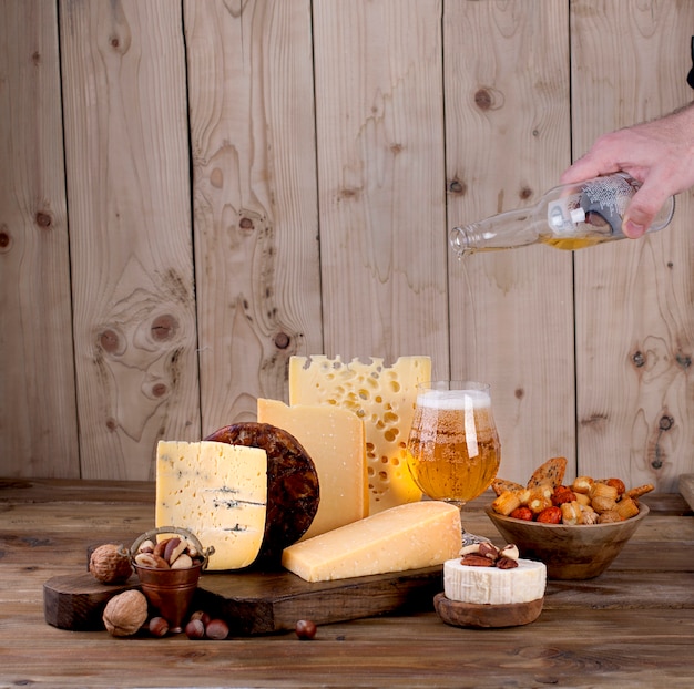 different cheese classic choice, on an old wooden board and nuts. Different cheese on an old wooden board. Dutch cheese and beer