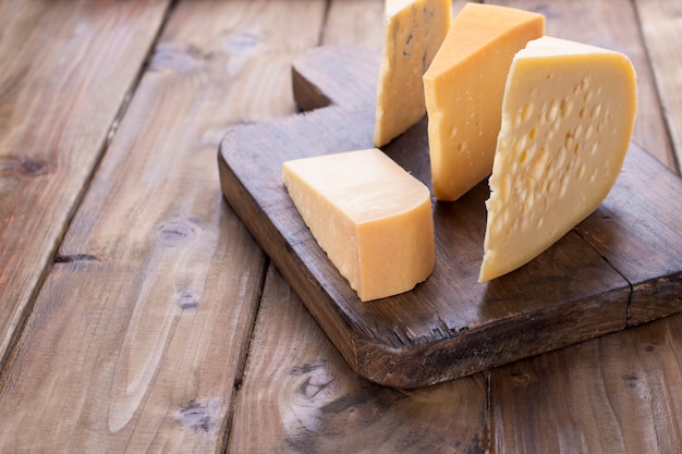 Different cheese on an old wooden board. Dutch cheese