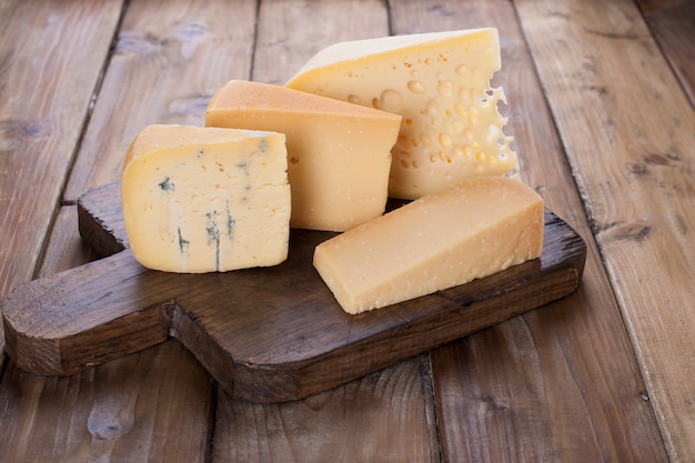 Different cheese on an old wooden board. Dutch cheese