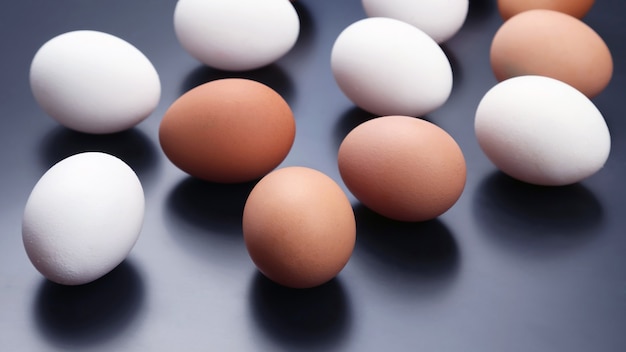 Photo different chicken eggs lie on dark background.  raw food for cooking