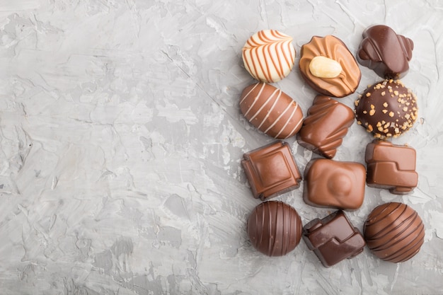 Different chocolate candies on a gray concrete background. top view, copy space.