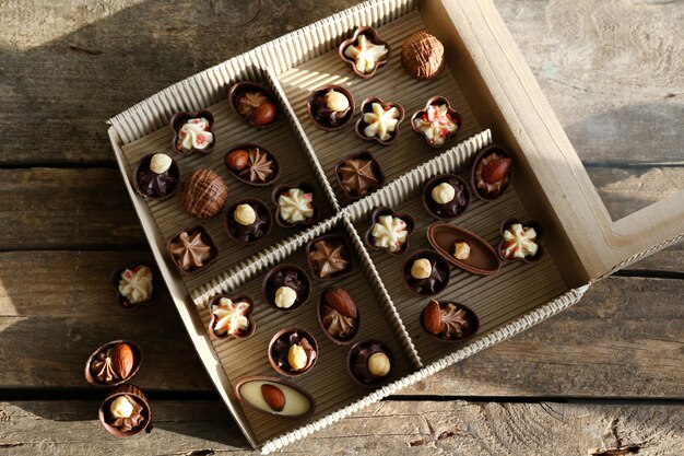 Diverse caramelle al cioccolato in scatola di carta su sfondo di legno, primi piani