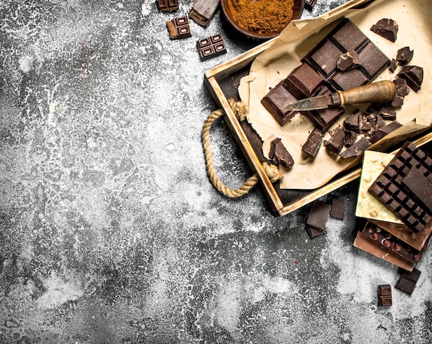 Different chocolate on tray on rustic table.