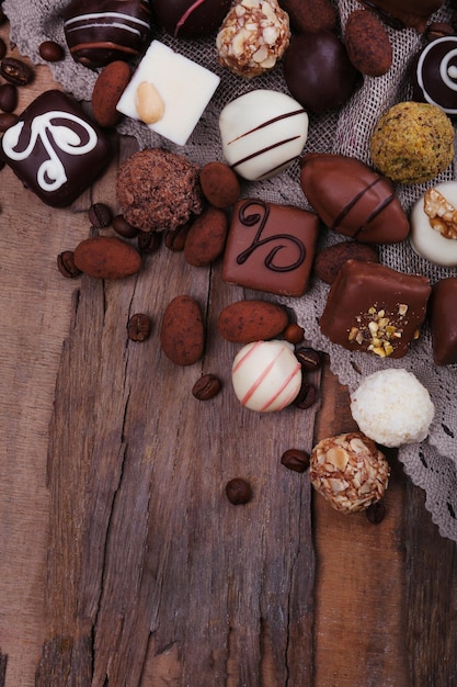 Different chocolates with coffee beans on grey fabric on wooden background