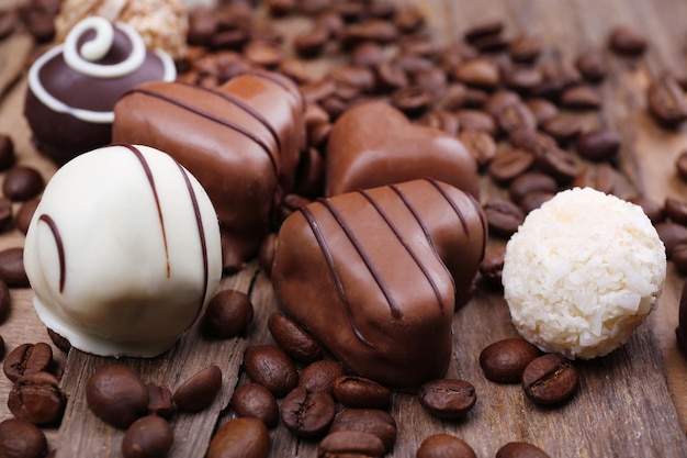 Different chocolates with coffee beans on wooden textured background