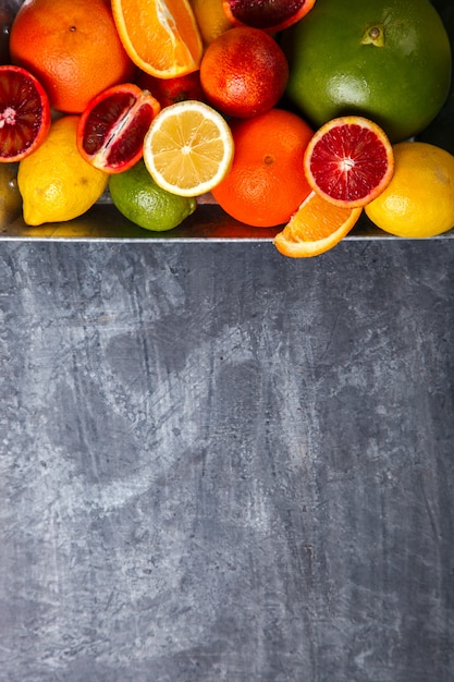 Different Citrus Fruit in a Metal tray on Gray Background .