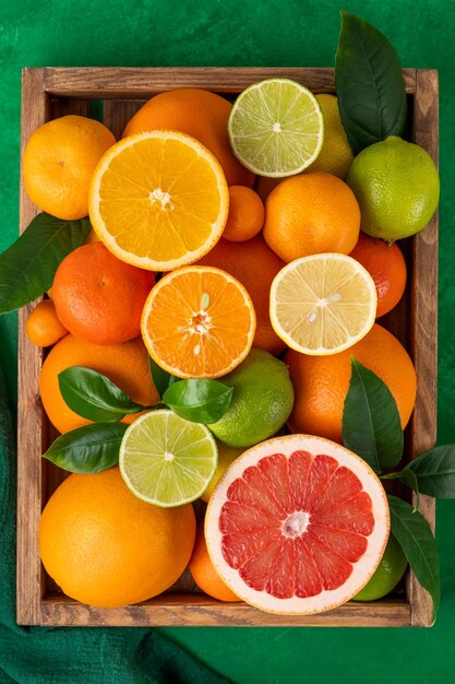 Different citrus fruits with leaves in a wooden box on a concrete background Healthy food Top view