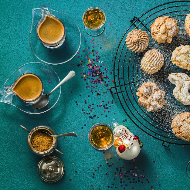 Different classic Italian homemade almond cookies with espresso coffee and glasses of sweet liquor on the table, Christmas decor