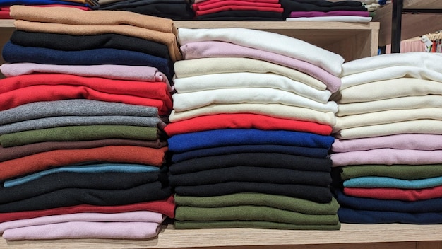 Different color fabrics stacked one on top of the other in a stack selling textiles in a store