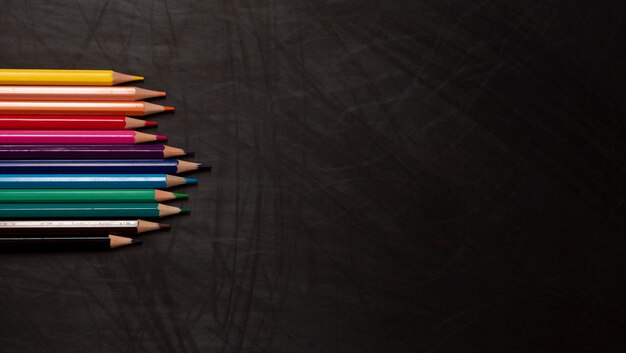 Different color wooden pencils on black chalkboard background