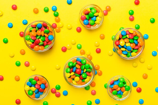 Different colored round candy in bowl and jars top view of large variety sweets and candies with copy space