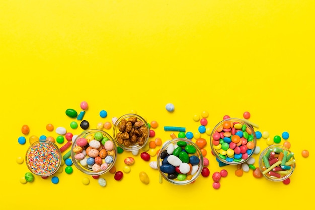 ボウルと瓶の中の異なる色の丸いキャンディー コピー スペースを持つ多種多様なお菓子やキャンディーの上面図
