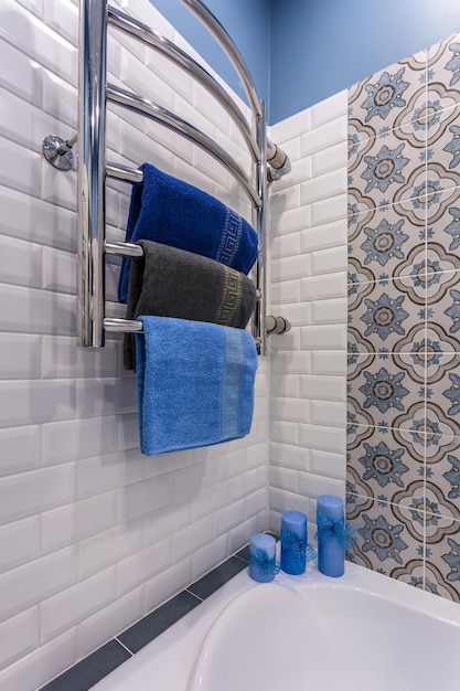 Different colored towels on a hanger in the bathroom with candles