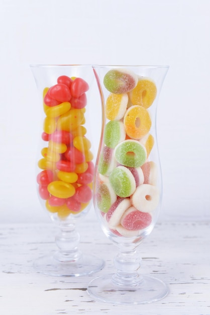 Different colorful fruit candy in glasses on table on light background