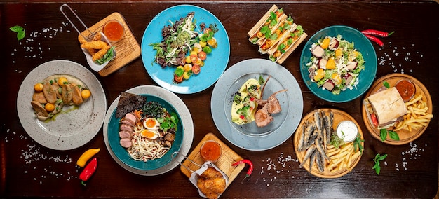 Different colorful meals on dark wooden table in the restaurant